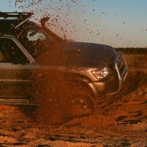 SUV driving through sand, kicking up dust in a thrilling off-road scene.