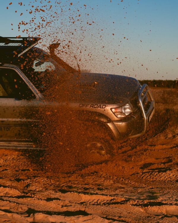SUV driving through sand, kicking up dust in a thrilling off-road scene.